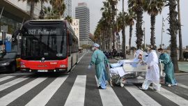 El personal médico del Hospital del Mar lleva a la paciente del COVID-19, Marta Pascual, de 72 años, de vuelta al hospital tras tomar un poco de aire fresco junto al mar, en la explanada de la playa de la Barceloneta en Barcelona.