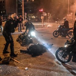La policía motorizada llega para atender a su colega herido durante una manifestación contra la violencia policial en un suburbio de Atenas. | Foto:Louisa Gouliamaki / AFP