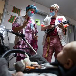 Dos payasos de la ONG Sunrise Media (Medical Smile) actúan para un bebé en el ala infantil del Hospital Son Llatzer de Palma de Mallorca. | Foto:Jaime Reina / AFP