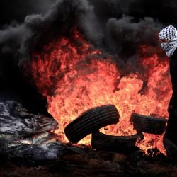 Un manifestante palestino camina frente a neumáticos quemados durante los enfrentamientos con las fuerzas israelíes tras una manifestación semanal contra la expropiación de tierras palestinas por parte de Israel en la aldea de Kfar Qaddum, cerca de la ciudad de Naplusa en Cisjordania. | Foto:Oday Daibes / APA Imágenes a través de ZUMA Wire / DPA