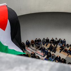 Una bandera palestina ondea sobre los árabes israelíes sentados en esteras juntos asistiendo al sermón musulmán de las oraciones del viernes, durante una manifestación en la ciudad mayoritariamente árabe de Umm al-Fahm en el norte de Israel contra el crimen organizado y pidiendo a la policía israelí que detener una ola de violencia intracomunitaria. | Foto:Ahmad Gharabli / AFP