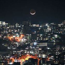 Una vista general muestra una luna creciente sobre las casas en la ladera de una colina en Aizawl, la capital del estado de Mizoram, en el noreste de la India. | Foto:Sajjad Hussain / AFP
