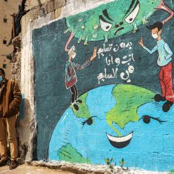 Un palestino y su hijo están parados junto a un grafiti en una pared que dice  | Foto:Mohammed Abed / AFP