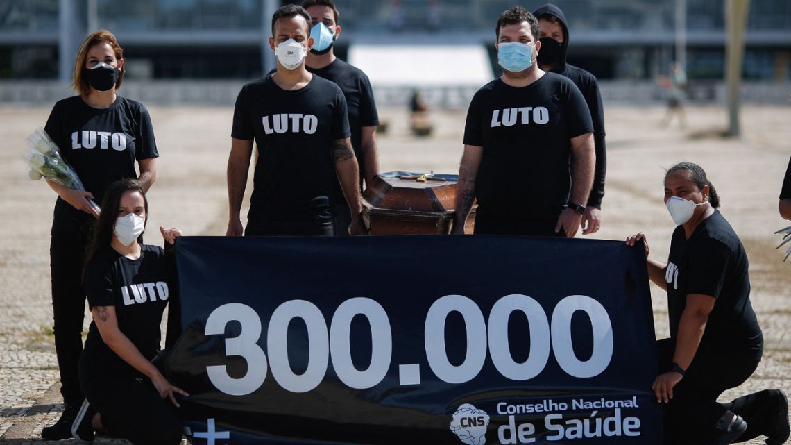 Health professionals carry a coffin to protest the death of 300,000 people from Covid-19, at the square of the Three Powers, in Brasilia, on March 25, 2021. 
