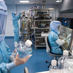 Empleados vestidos con trajes para salas blancas prueban los procedimientos para la fabricación del ARN mensajero (ARNm) para la vacuna Covid-19 en el nuevo sitio de fabricación de la empresa alemana BioNTech en Marburg, Alemania central. | Foto:Thomas Lohnes / AFP