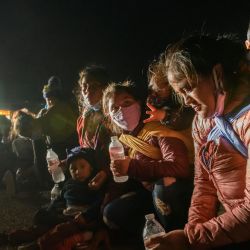 Mujeres y niños inmigrantes que llegaron ilegalmente a través del río Grande desde México descansan en un puesto de control de procesamiento improvisado antes de ser detenidos en un centro de detención por agentes de la patrulla fronteriza en la ciudad fronteriza de Roma. | Foto:Ed Jones / AFP