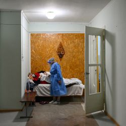 Margaret Melnic, de 67 años, jefa de la sección COVID-19 del hospital, habla con una mujer sospechosa de estar infectada con coronavirus que descansa en una cama colocada en el pasillo de la sección de enfermedades infecciosas COVID-19 del hospital regional en la ciudad de Leova. | Foto:AFP