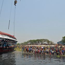 Los espectadores y familiares se reúnen después de que las autoridades recuperaron el bote volcado en el río Shitalakshya, en Narayanganj. | Foto:Munir Uz zaman / AFP