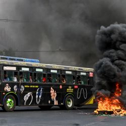 Esta fotografía muestra un autobús pasando una barricada improvisada en llamas, erigida por manifestantes que se manifestaban contra el golpe militar, en el municipio de Tamwe de Yangon. | Foto:STR / AFP