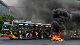 Esta fotografía muestra un autobús pasando una barricada improvisada en llamas, erigida por manifestantes que se manifestaban contra el golpe militar, en el municipio de Tamwe de Yangon.