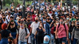 People wearing protective face masks walk by Avenida Brasil, near the Constitución train station in Buenos Aires City, on April 6, 2021.