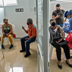 Una mujer es inoculada con la vacuna Oxford / AstraZeneca contra COVID-19 en un centro de vacunación, mientras otras personas esperan, en medio de la pandemia del nuevo coronavirus, en Medellín, Colombia. | Foto:Joaquin Sarmiento / AFP