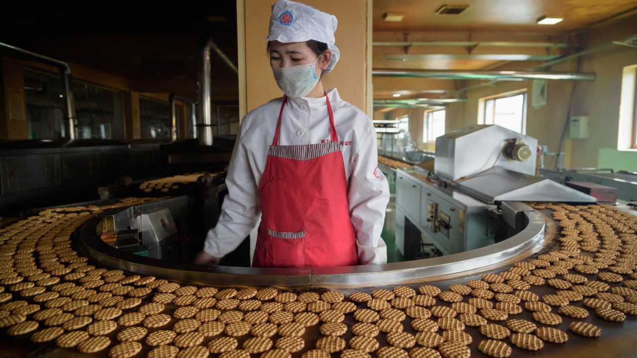 Un trabajador se para frente a una máquina en una línea de producción de pasteles de la marca  | Foto:STR / AFP