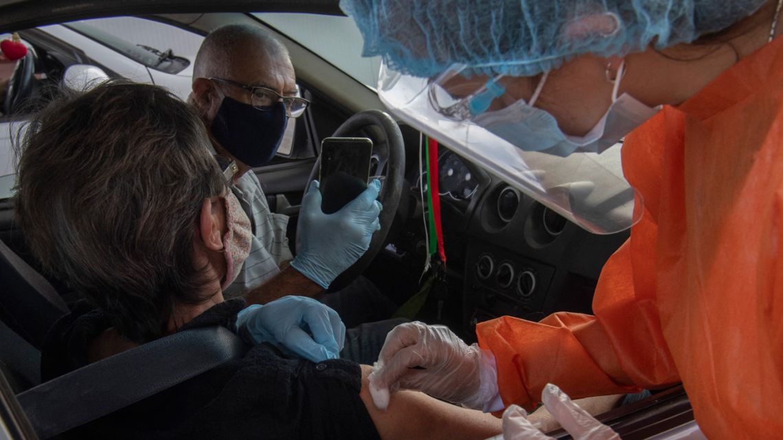 In this file photo taken on April 08, 2021 a man takes a pictures of his wife being inoculated with the CoronaVac vaccine, developed by China's Sinovac laboratory against COVID-19, at a vaccination centre mounted at Carrasco airport in Ciudad de la Costa, Canelones, Uruguay. 