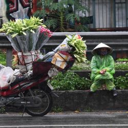 Una vendedora ambulante espera que los clientes compren flores junto a su motocicleta en Hanoi. | Foto:Nhac Nguyen / AFP