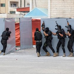Los miembros palestinos de las fuerzas de seguridad de Hamas se protegen detrás de una pared de lona mientras realizan maniobras mientras muestran sus habilidades durante una ceremonia de graduación de la policía en la ciudad de Gaza. | Foto:Mahmud Hams / AFP