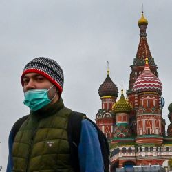 Un hombre con una máscara facial camina cerca de la torre Spasskaya del Kremlin y la catedral de San Basilio en Moscú, mientras la ciudad se prepara para celebrar el 76 aniversario de la victoria sobre la Alemania nazi durante la Guerra Mundial. II. | Foto:Yuri Kadobnov / AFP