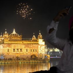 Un devoto sij toma fotografías de fuegos artificiales con motivo del aniversario del nacimiento de Guru Arjan Dev en el Templo Dorado iluminado en Amritsar. | Foto:Narinder Nanu / AFP