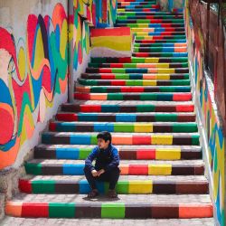 Un niño palestino sentado en escalones decorados con colores vibrantes en el barrio al-Daraj de la ciudad de Gaza. | Foto:Mohammed Abed / AFP