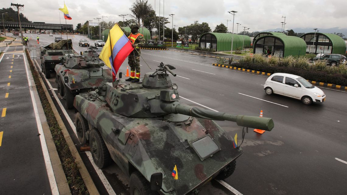 A soldier rises a Colombian flag on an Army tank in the outskirts of Bogotá on May 4, 2021. 