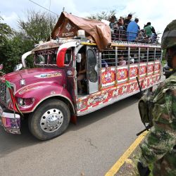 Un autobús pasa junto a los soldados que hacen guardia cerca de una barricada que bloquea la carretera Panamericana luego de una protesta contra el gobierno provocada por un proyecto de reforma tributaria ahora abandonado, en Cali, Colombia. | Foto:Luis Robayo / AFP