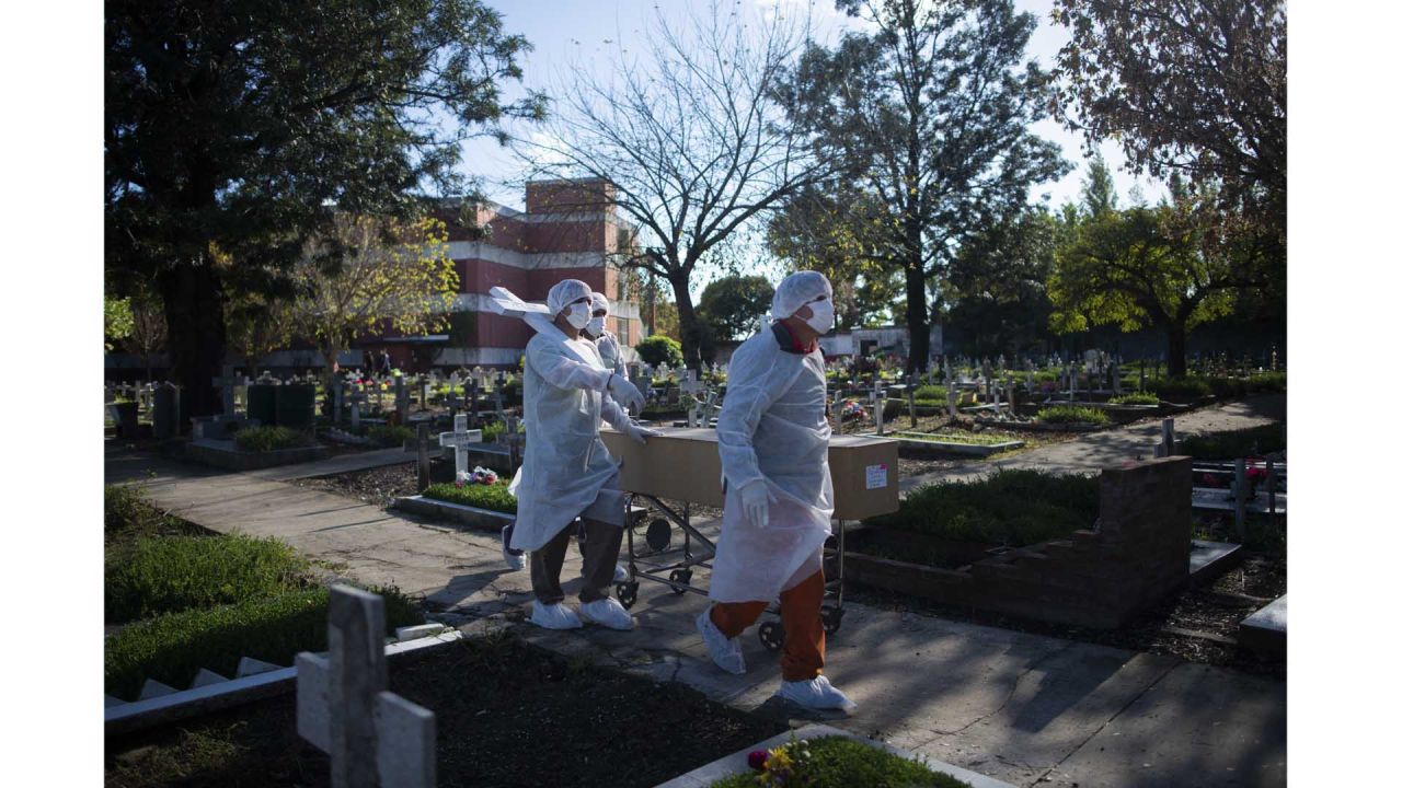 Trabajadores funerarios trasladan el ataúd de una víctima de Covid-19 en un cementerio de la provincia de Buenos Aires, Argentina, mayo del 2021. | Foto:Mario Defina