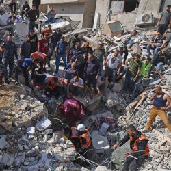 Los paramédicos palestinos buscan sobrevivientes bajo los escombros de un edificio destruido en la ciudad de Gaza, luego del bombardeo masivo israelí del enclave controlado por Hamas. | Foto:Mahmud Hams / AFP