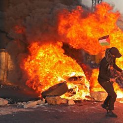 Manifestantes palestinos queman neumáticos durante una protesta contra la tensión en Jerusalén y los combates entre Israel y Gaza, en la ocupada Cisjordania, cerca del asentamiento de Beit El junto a Ramallah. | Foto:Abbas Momani / AFP