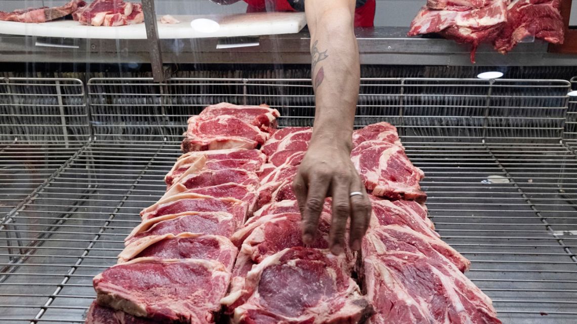 A butcher reaches for a cut of meat at a shop in Buenos Aires.