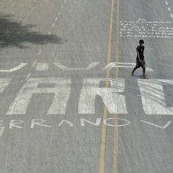 Un hombre camina sobre una pintura callejera que dice  | Foto:Luis Robayo / AFP