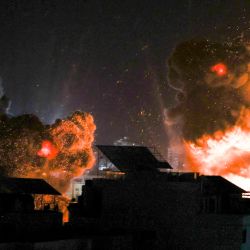 Las explosiones iluminan el cielo nocturno sobre los edificios en la ciudad de Gaza mientras las fuerzas israelíes bombardean el enclave palestino. | Foto:Mahmud Hams / AFP