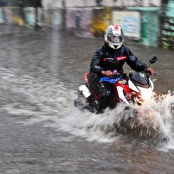 Un hombre conduce una motocicleta por una calle anegada tras las fuertes lluvias del ciclón Tauktae en Mumbai. | Foto:Indranil Mukherjee / AFP