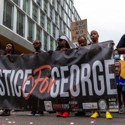 Las personas sostienen una pancarta mientras marchan durante un evento en memoria de George Floyd en Minneapolis, Minnesota. | Foto:Kerem Yucel / AFP