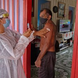 Joao Aquino Filho es vacunado por un trabajador de la salud con una dosis de la vacuna COVID-19 Oxford-AstraZeneca en la comunidad de Nossa Senhora Livramento en las orillas del Río Negro cerca de Manaos, estado de Amazonas, Brasil. | Foto:Michael Dantas / AFP