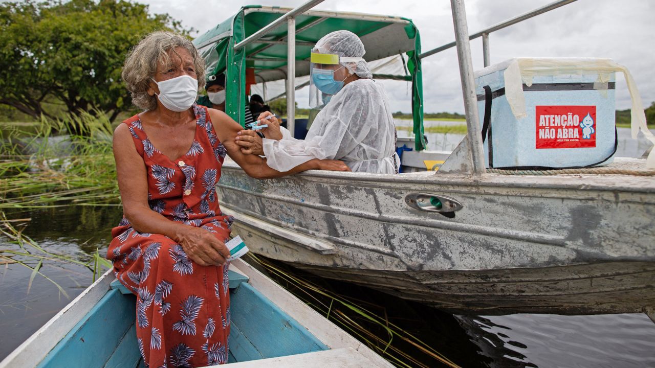 Olga D'arc Pimentel, de 72 años, es vacunada por un trabajador de la salud con una dosis de la vacuna COVID-19 Oxford-AstraZeneca en la comunidad de Nossa Senhora Livramento a orillas del Río Negro cerca de Manaus, estado de Amazonas, Brasil. | Foto:Michael Dantas / AFP