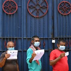 Los trabajadores sostienen documentos mientras esperan su turno para recibir la primera dosis de la vacuna Covishield contra el coronavirus Covid-19 en un autobús de pasajeros convertido en un centro de vacunación móvil en un mercado mayorista en Calcuta. | Foto:Dibyangshu Sarkar / AFP