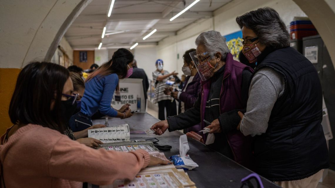 Officials assist a voter at a polling location in Mexico City, on Sunday, June 6, 2021.