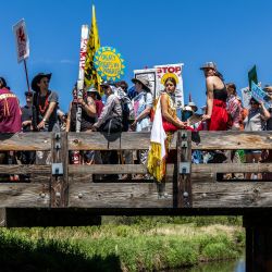 Activistas climáticos y miembros de la comunidad indígena se reúnen en lo alto del puente después de participar en una ceremonia tradicional del agua durante una manifestación y marcha para protestar por la construcción del oleoducto Enbridge Line 3 en Solvay, Minnesota. | Foto:Kerem Yucel / AFP
