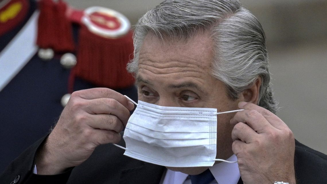 President Alberto Fernández puts his face mask on after delivering a joint press conference with Spain's Prime Minister Pedro Sánchez (out of shot) at the Casa Rosada in Buenos Aires on June 9, 2021. 