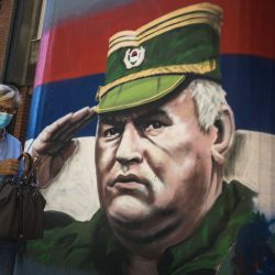 Una mujer pasa junto a un mural que representa al exjefe militar serbio de Bosnia Ratko Mladic, en Belgrado. | Foto:Andrej Isakovic / AFP