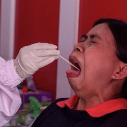 Una mujer tiene un reflejo nauseoso mientras un médico le toma una muestra bucal durante una campaña de pruebas de COVID-19. | Foto:Slamet Riyadi / ZUMA Wire / DPA