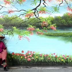 Una mujer se sienta frente a una tienda cerrada en Hanoi. | Foto:Manan Vatsyayana / AFP