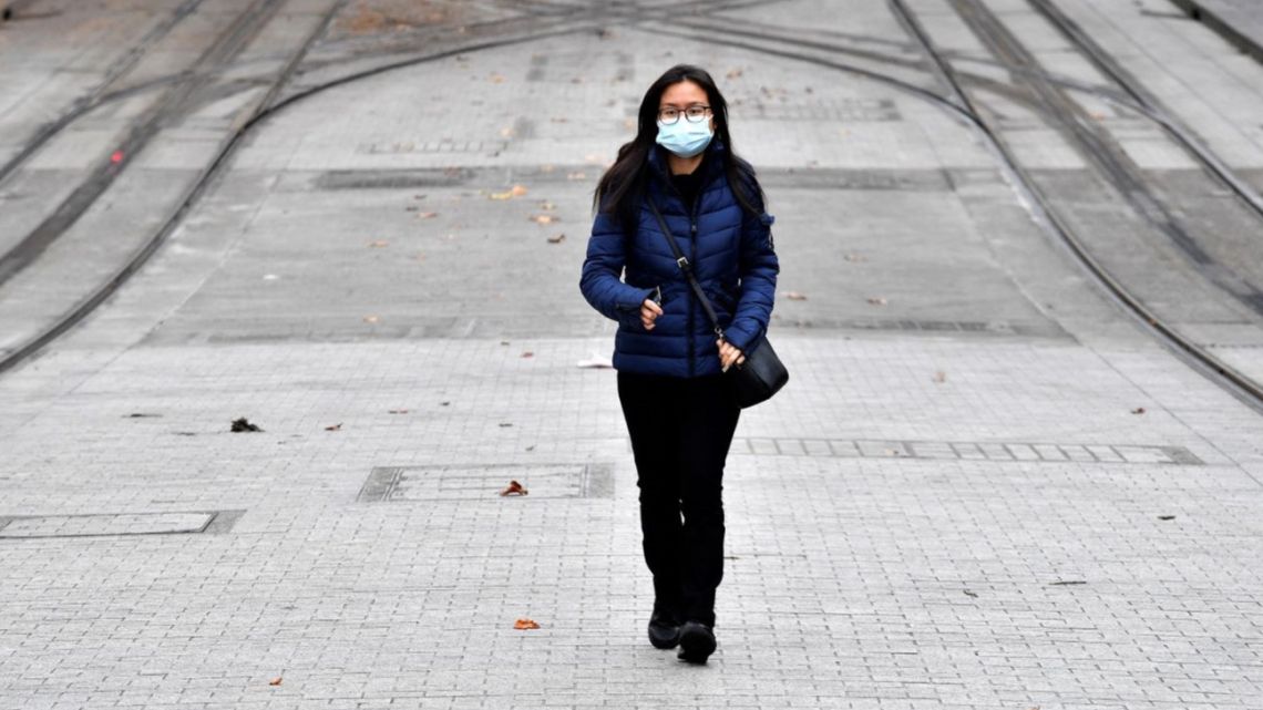 A woman wearing a face mask walks towards a light rail station in Sydney on June 23, 2021, as residents were largely banned from leaving the city to stop a growing outbreak of the highly contagious Delta Covid-19 variant spreading to other regions.