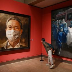 Un visitante observa las pinturas del experto chino en enfermedades respiratorias Zhong Nanshan, que lideró la lucha contra el coronavirus Covid-19 en China, del artista Feng Shaoxie. | Foto:Greg Baker / AFP