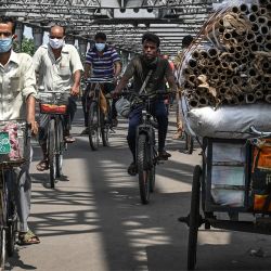 Los transeúntes cruzan el puente de Howrah en sus bicicletas mientras el gobierno estatal suspende el transporte público regular durante el bloqueo impuesto para frenar la propagación del coronavirus Covid-19, en Calcuta. | Foto:Dibyangshu Sarkar / AFP