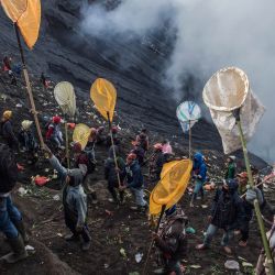 La gente trata de atrapar las ofrendas lanzadas por la gente de la tribu Tengger desde la cima del volcán activo del Monte Bromo en Probolinggo, provincia de Java Oriental. | Foto:Juni Kriswanto / AFP