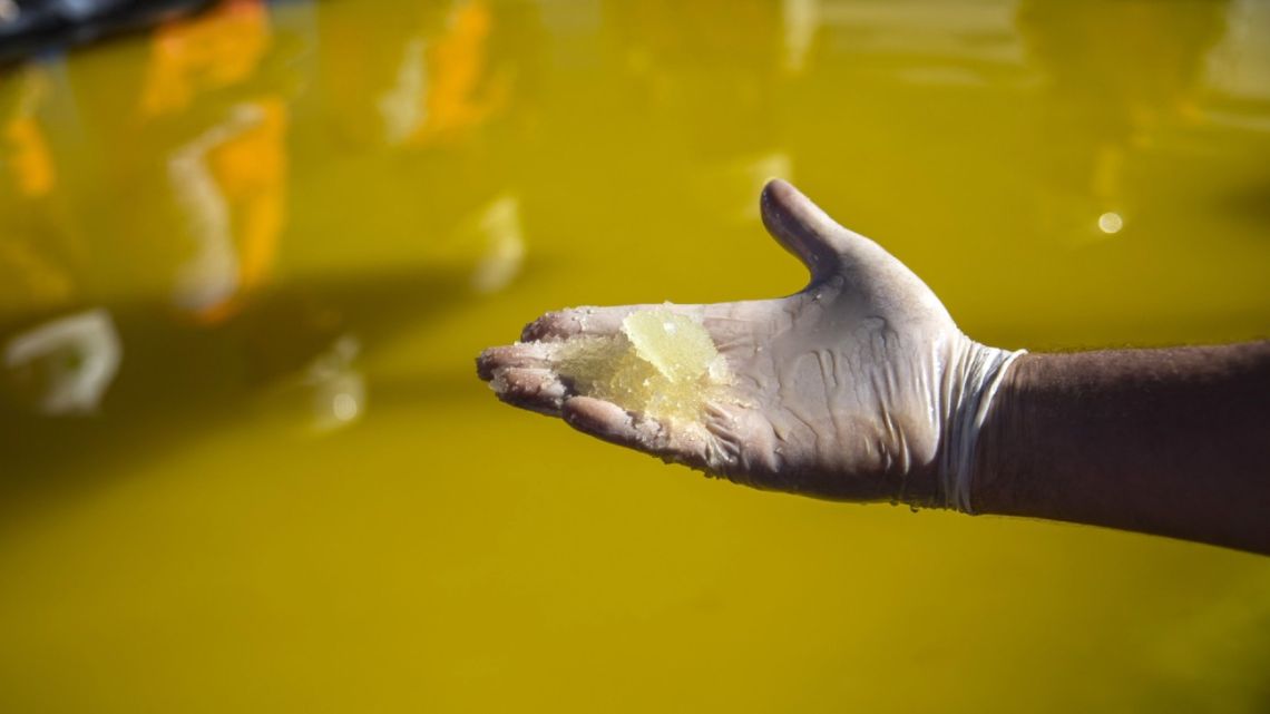 A visitors holds lithium concentrate for a photograph at a Sociedad Química y Minera de Chile (SQM) lithium mine on the Atacama salt flat in the Atacama Desert, Chile.