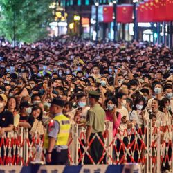 La gente mira un espectáculo de luces en el paseo del Bund en Shanghái, en la víspera del centenario del Partido Comunista Chino. | Foto:Hector Retamal / AFP