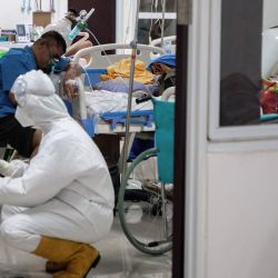 Un trabajador sanitario con traje de protección personal fija una bombona de oxígeno junto a un paciente de COVID-19 en el complejo del Hospital de Urgencias Wisma Atlet Covid-19. | Foto:Foto: Risa Krisadhi / SOPA Images vía ZUMA Wire / DPA