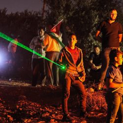 Manifestantes palestinos utilizan láser durante una manifestación contra el puesto de avanzada de los colonos israelíes de Eviatar, en la localidad de Beita, cerca de la ciudad ocupada de Naplusa, en Cisjordania. | Foto:Jaafar Ashtiyeh / AFP